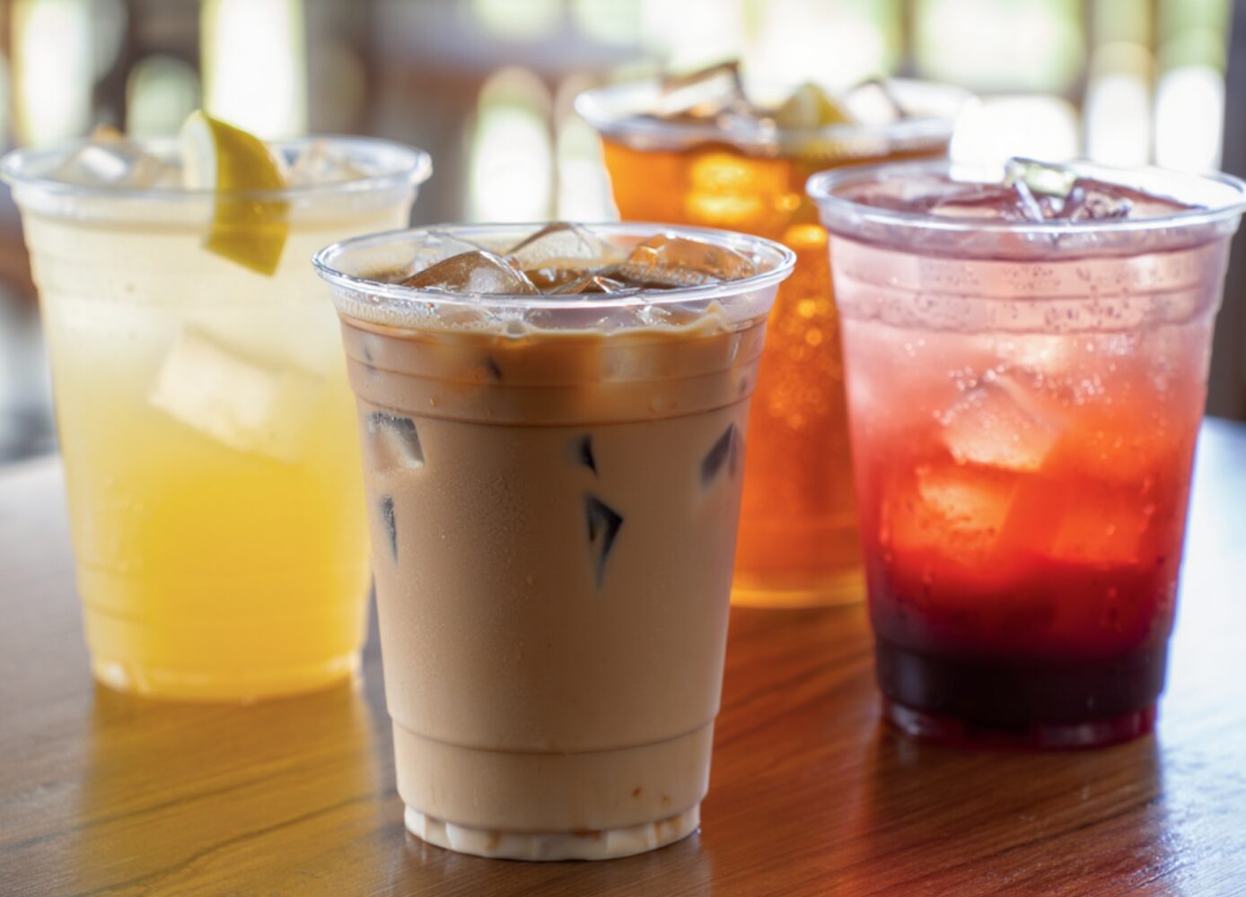 beverages in plastic cups sit on a table in a sunny cafe