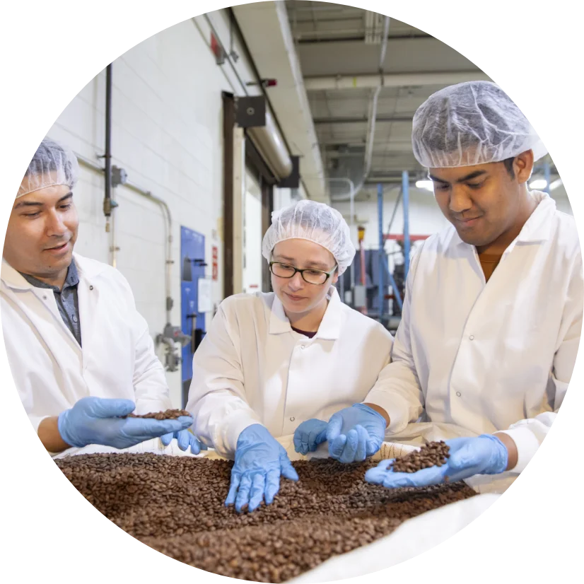 group of people in white coats and blue gloves involved in manufacturing ingredients for beverages