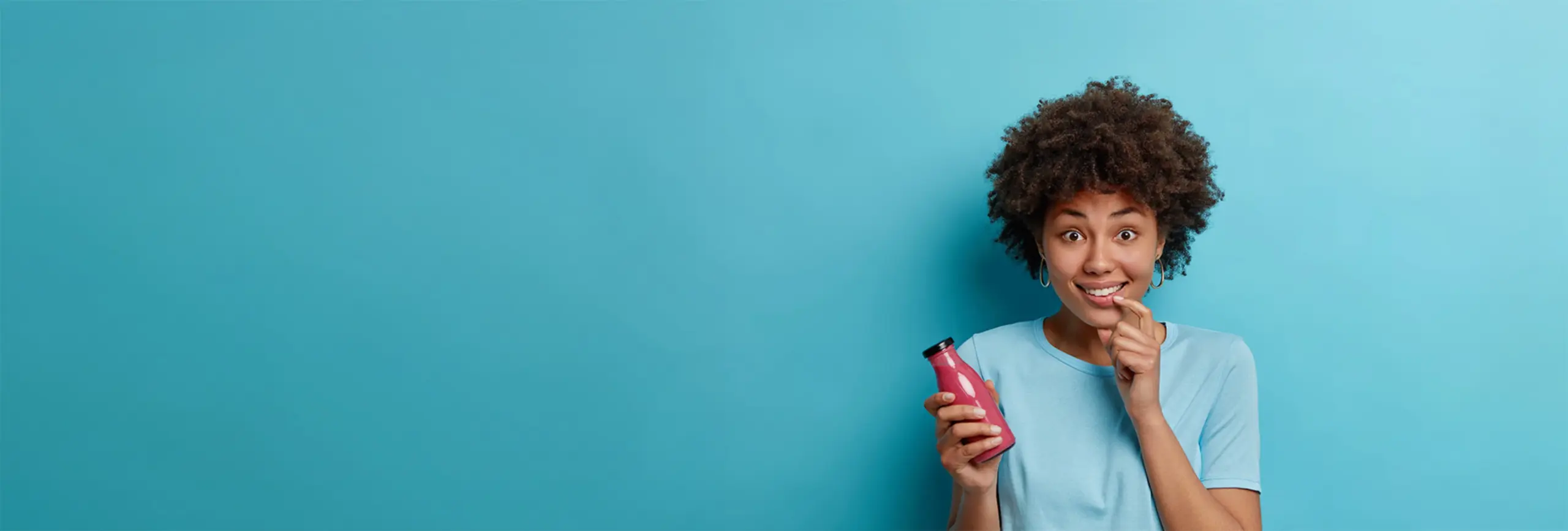 woman standing against a blue wall holding a can of soda