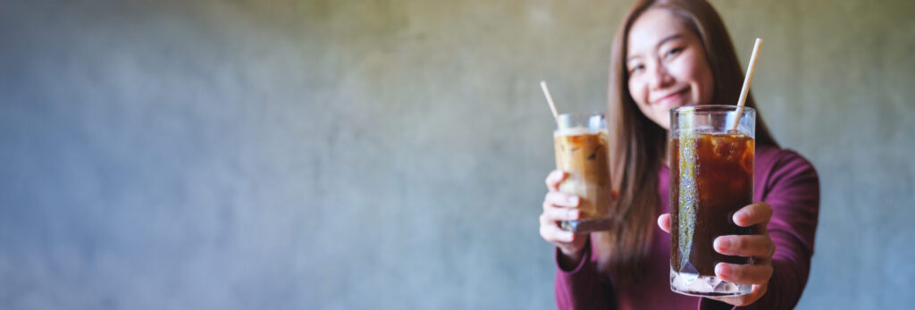 woman holding two glasses of liquid in front of her face