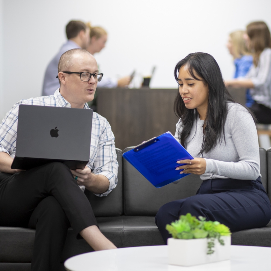 wo people sitting on a couch with laptops while enjoying beverages