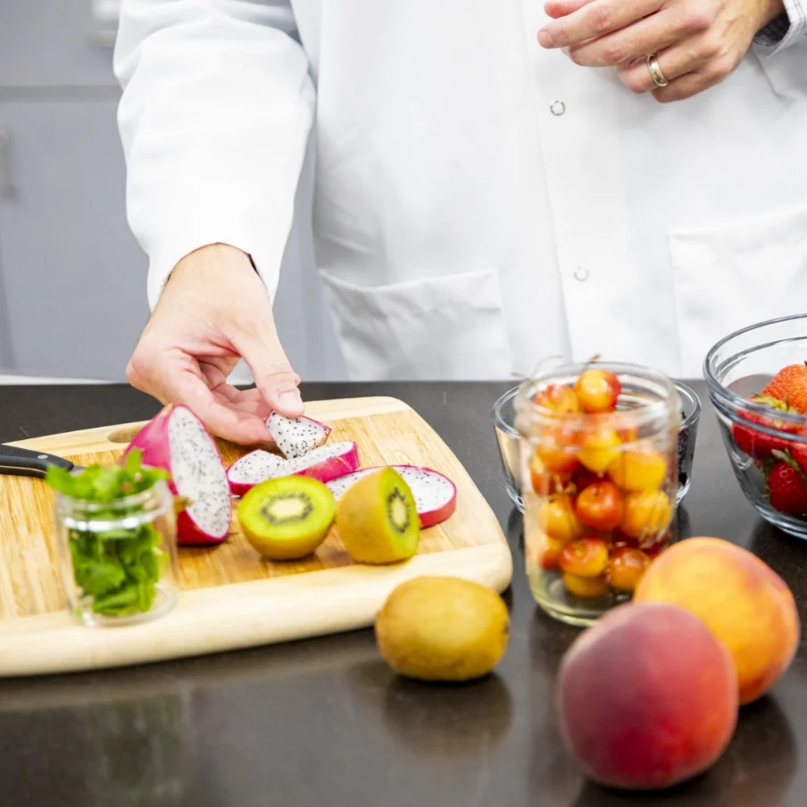 man in a chef's coat cutting up ingredients on a cutting board