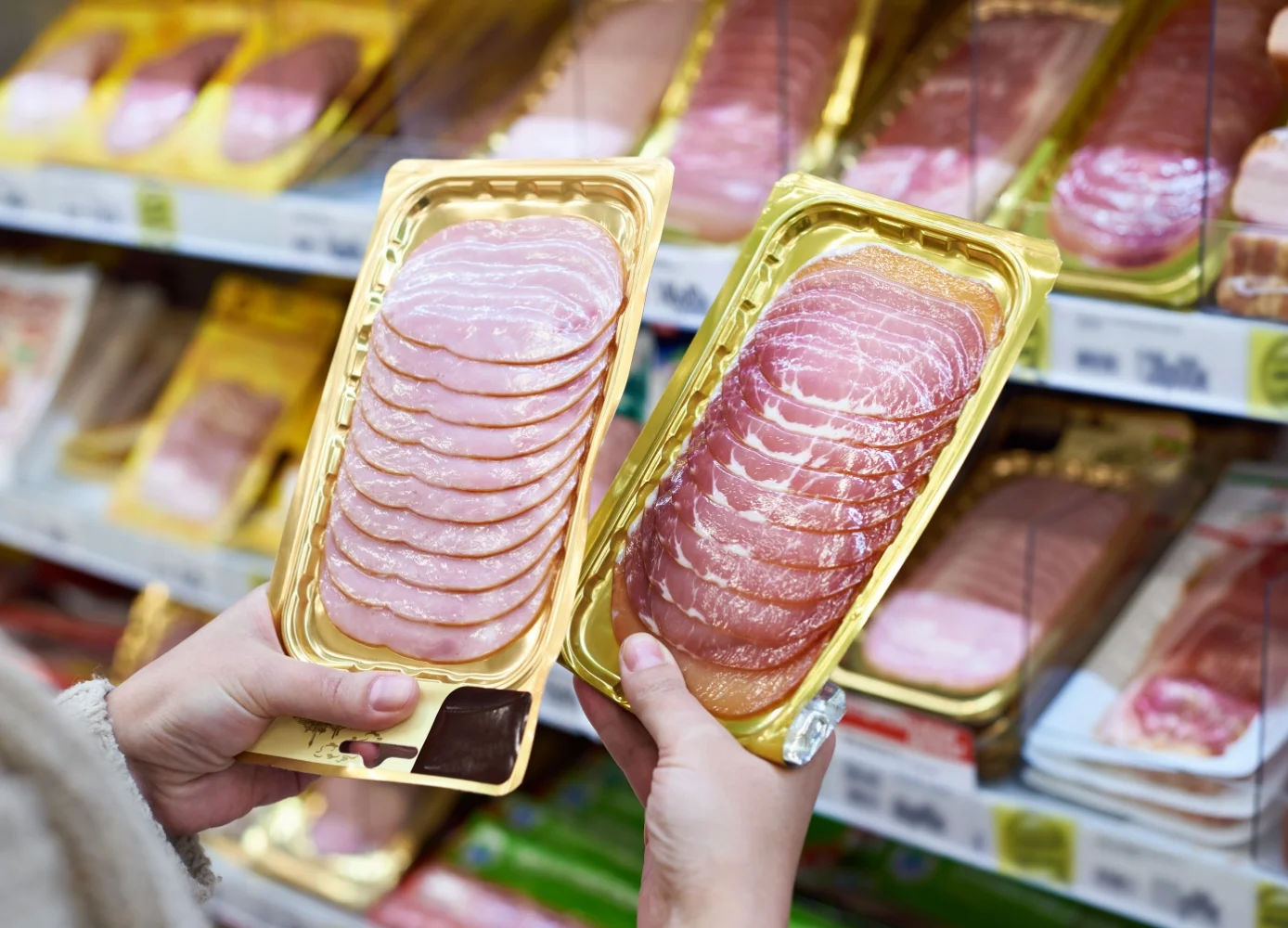 person holding up a package of meat in a store while shopping for ingredients
