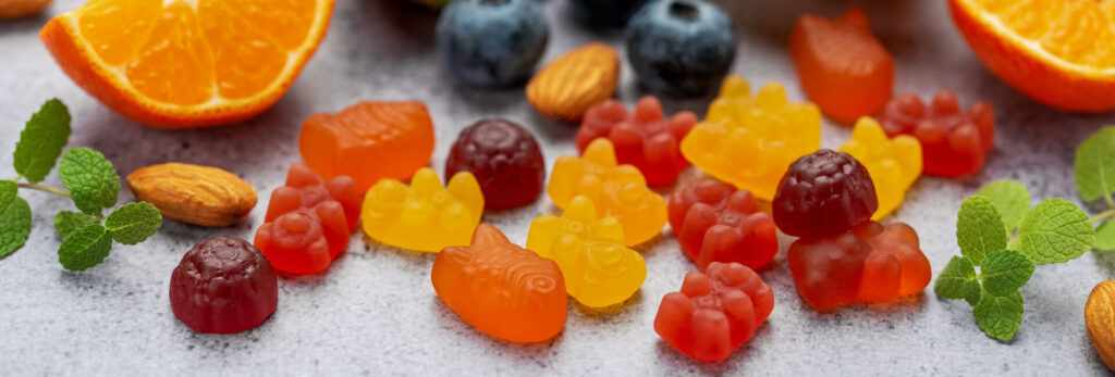 Assorted fruit-flavored gummy vitamins with citrus, blueberries, almonds, and mint.